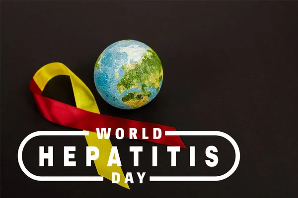 Червона і жовта стрічка поблизу земної кулі і Всесвітній день гепатиту, що розкладається на чорному — стокове фото