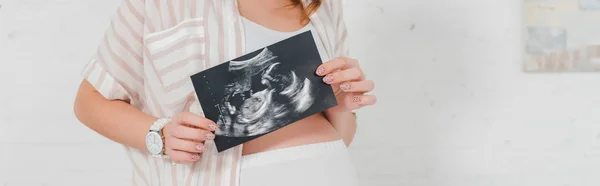 Cropped view of pregnant girl showing ultrasound scan of baby, panoramic shot — Stock Photo