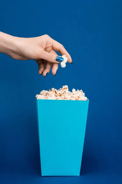 Vista ritagliata di donna che tiene popcorn su sfondo blu — Foto stock