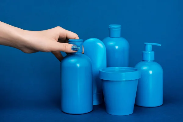 Vue recadrée de la femme tenant bouteille avec shampooing sur fond bleu — Photo de stock