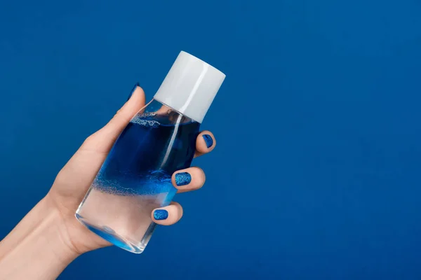Abgeschnittene Ansicht einer Frau, die micellar Reinigungswasser isoliert auf blau hält — Stockfoto