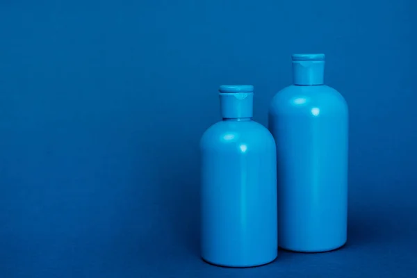Пластикові пляшки з шампунем на синьому фоні з копією простору — стокове фото
