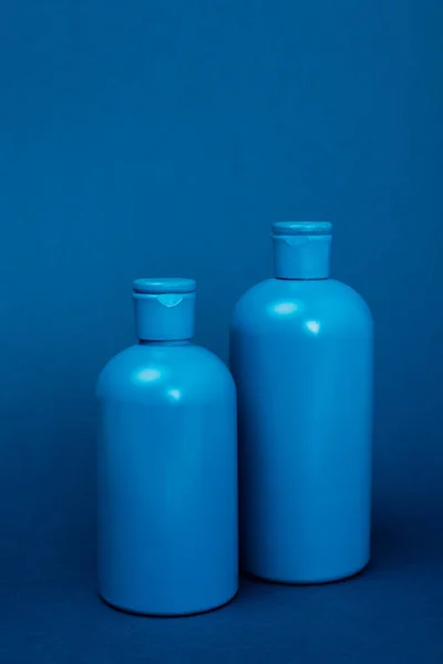 Garrafas de plástico com shampoo no fundo azul com espaço de cópia — Fotografia de Stock