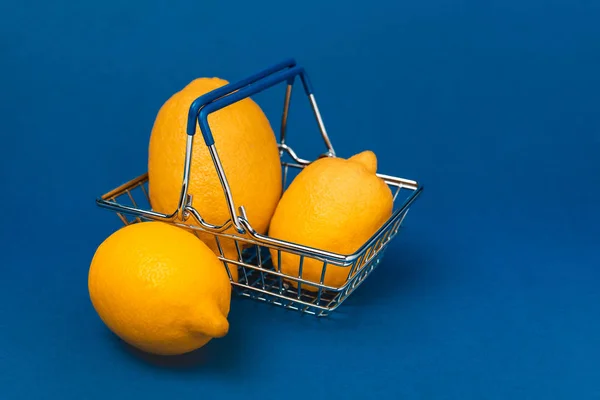 Panier avec des citrons entiers et biologiques sur fond bleu — Photo de stock