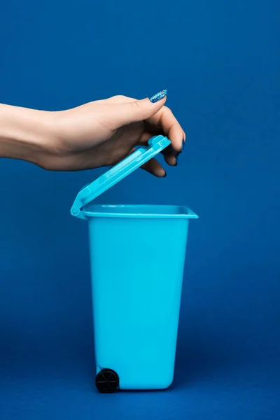 Vista cortada de mulher abrindo lata de lixo de brinquedo no fundo azul — Fotografia de Stock