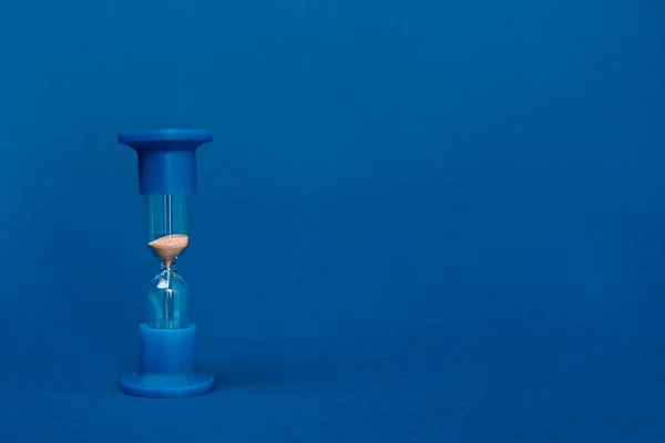 Яркие и красочные песочные часы на синем фоне с копированием пространства — стоковое фото