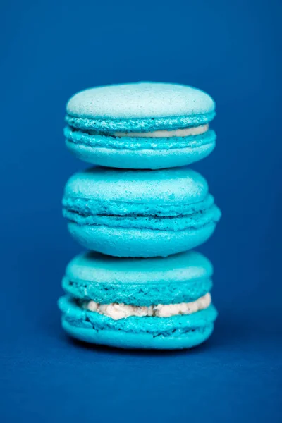Macarrones franceses dulces y sabrosos sobre fondo azul - foto de stock
