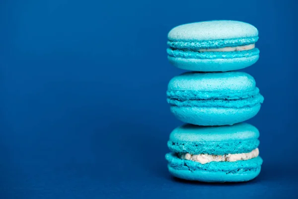 Tasty french macaroons on blue background with copy space — Stock Photo