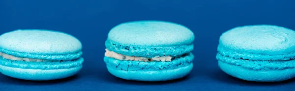 Panoramic shot of french macaroons on blue background — Stock Photo