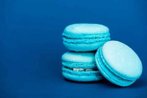 Tasty french macaroons on blue background with copy space — Stock Photo