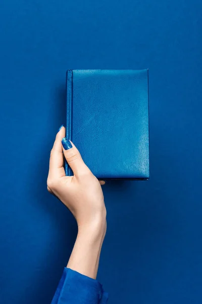 Обрезанный вид женщины, держащей ноутбук на синем фоне — стоковое фото