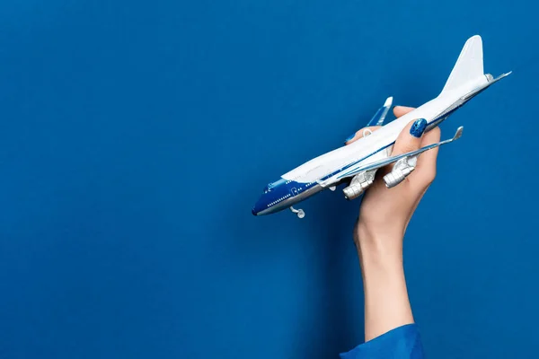 Cropped view of woman holding model of plane on blue background — Stock Photo