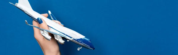 Panoramic shot of woman holding model of plane on blue background — Stock Photo