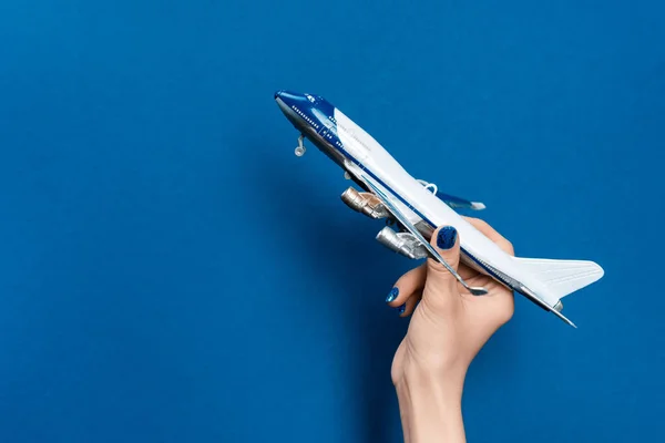 Cropped view of woman holding model of plane on blue background — Stock Photo