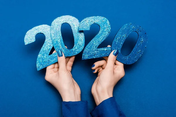 Cropped view of woman holding 2020 numbers on blue background — Stock Photo