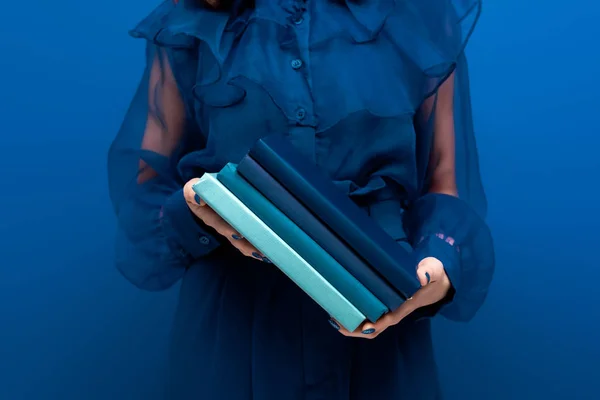 Обрезанный вид женщины, держащей книги на синем фоне — стоковое фото