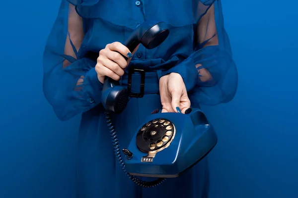 Обрезанный вид женщины, держащей ретро телефон на синем фоне — стоковое фото