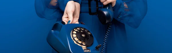 Tiro panorâmico de mulher segurando telefone retro no fundo azul — Fotografia de Stock