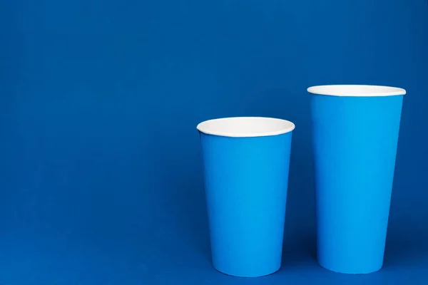 Copos de papel com refrigerante no fundo azul com espaço de cópia — Fotografia de Stock