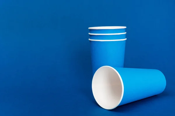 Vasos de papel vacíos sobre fondo azul con espacio de copia - foto de stock