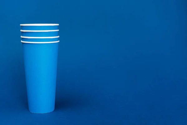 Яскраві паперові чашки на синьому фоні з пробілом для копіювання — стокове фото
