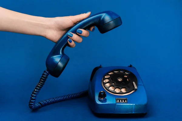 Cropped view of woman holding handset on blue background — Stock Photo