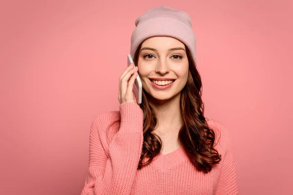 Glückliches Mädchen, das auf dem Smartphone spricht, während es isoliert auf rosa in die Kamera lächelt — Stockfoto