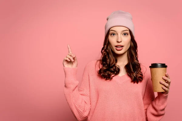 Ragazza pensierosa che mostra gesto idea mentre tiene il caffè per andare su sfondo rosa — Foto stock