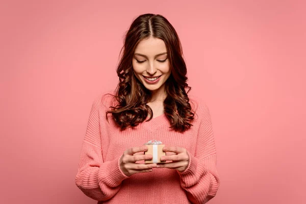 Glückliches Mädchen betrachtet kleine Geschenkschachtel isoliert auf rosa — Stockfoto