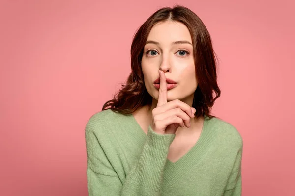 Chica seria mostrando gesto de silencio mientras mira a la cámara aislada en rosa - foto de stock