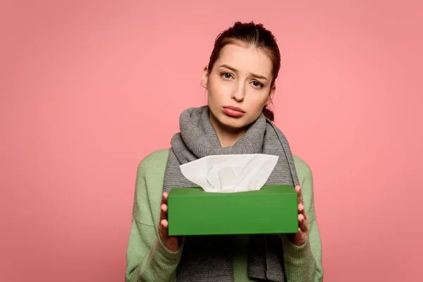 Mécontent, fille malade dans l'écharpe chaude prendre boîte de serviettes en papier isolé sur rose — Photo de stock