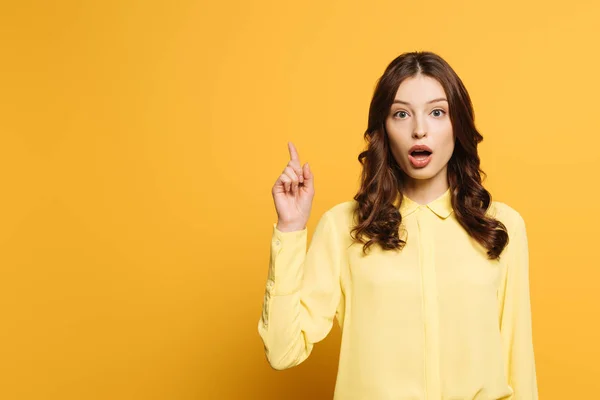 Überrascht Mädchen zeigt Idee Geste, während Blick in die Kamera auf gelbem Hintergrund — Stockfoto
