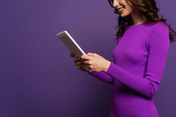 Cropped view of smiling young woman using digital tablet on purple background — Stock Photo