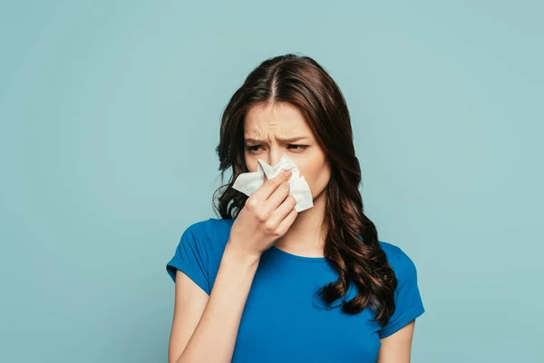 Chica enferma, disgustada limpiando la nariz con servilleta de papel aislada en azul - foto de stock