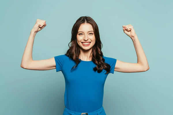 Fille gaie montrant geste gagnant tout en souriant à la caméra sur fond bleu — Photo de stock