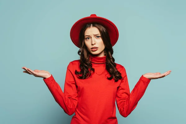 Confused girl showing shrug gesture while looking at camera on blue background — Stock Photo