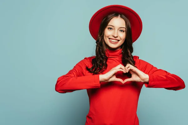 Glücklich stilvolles Mädchen zeigt Herz-Symbol mit Händen auf blauem Hintergrund — Stockfoto