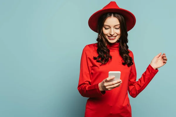 Allegra ragazza elegante sorridente mentre chatta su smartphone su sfondo blu — Foto stock