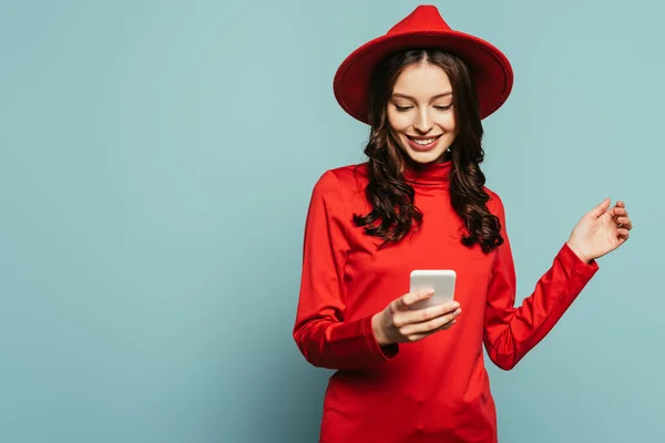 Joyeuse fille élégante souriant tout en bavardant sur smartphone sur fond bleu — Photo de stock