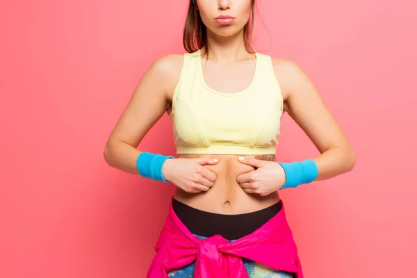 Ausgeschnittene Ansicht einer unzufriedenen Sportlerin, die ihren Körper auf rosa Hintergrund berührt — Stockfoto