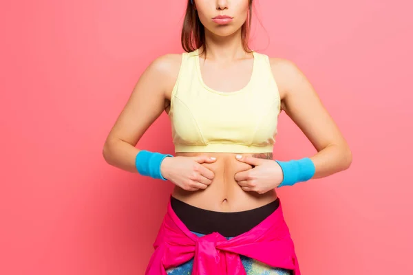 Vista recortada de la deportista disgustada tocando su cuerpo sobre fondo rosa - foto de stock