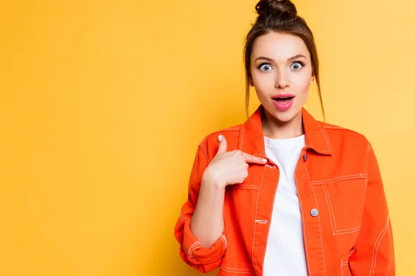 Shocked girl pointing with finger at herself while looking at camera on yellow background — Stock Photo