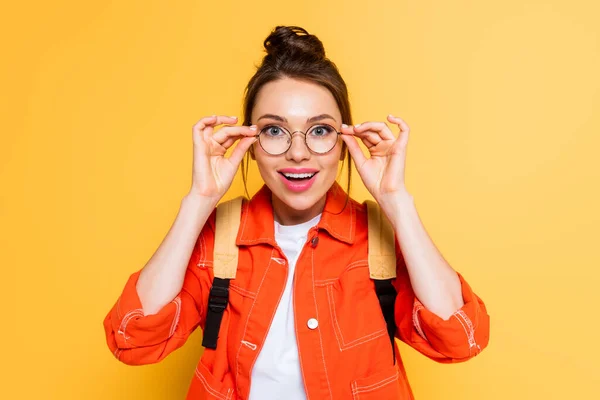 Überraschter Student berührt Brille beim Anblick der Kamera auf gelbem Hintergrund — Stockfoto