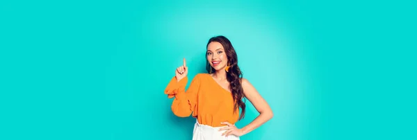 Panoramic shot of cheerful, stylish girl showing idea gesture while standing with hand on hip on turquoise background — Stock Photo