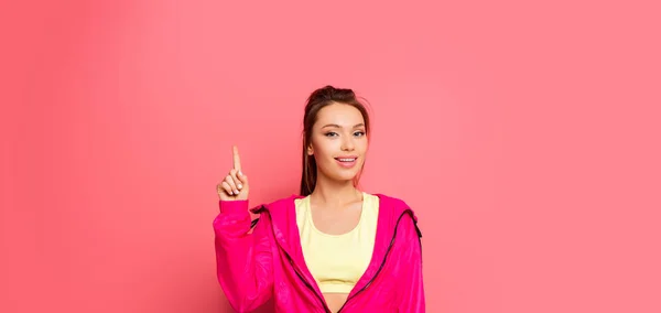 Plan panoramique de jeune sportive souriante montrant geste d'idée sur fond rose — Photo de stock