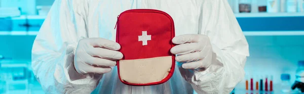 Prise de vue panoramique du scientifique en combinaison Hazmat tenant la trousse de premiers soins — Photo de stock