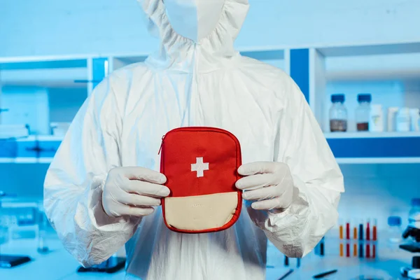 Cropped view of scientist in hazmat suit holding first aid kit — Stock Photo