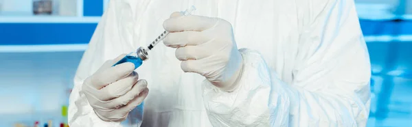 Panoramic shot of scientist in latex gloves holding syringe and bottle with vaccine — Stock Photo