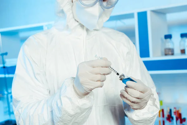Обрезанный вид ученого в латексных перчатках, держащих шприц и бутылку с вакциной — стоковое фото