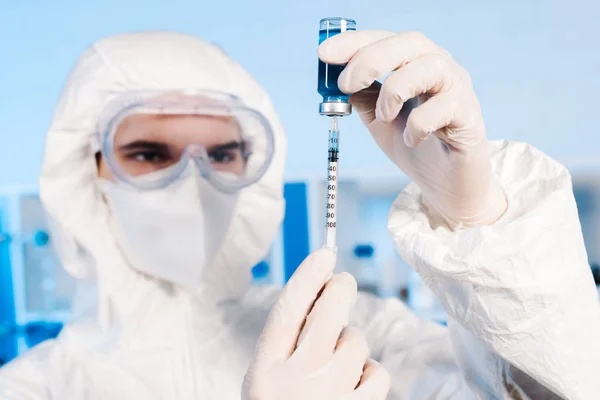 Selective focus of scientist holding syringe and bottle with vaccine — Stock Photo